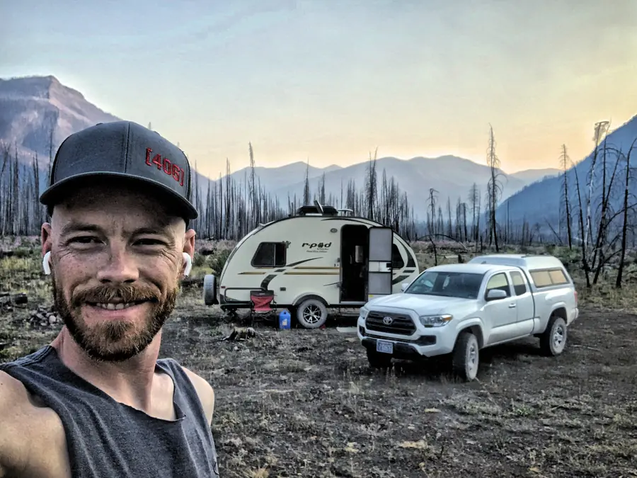 Mark Ulett at a backcountry campsite, Montana mountains and r-pod behind him